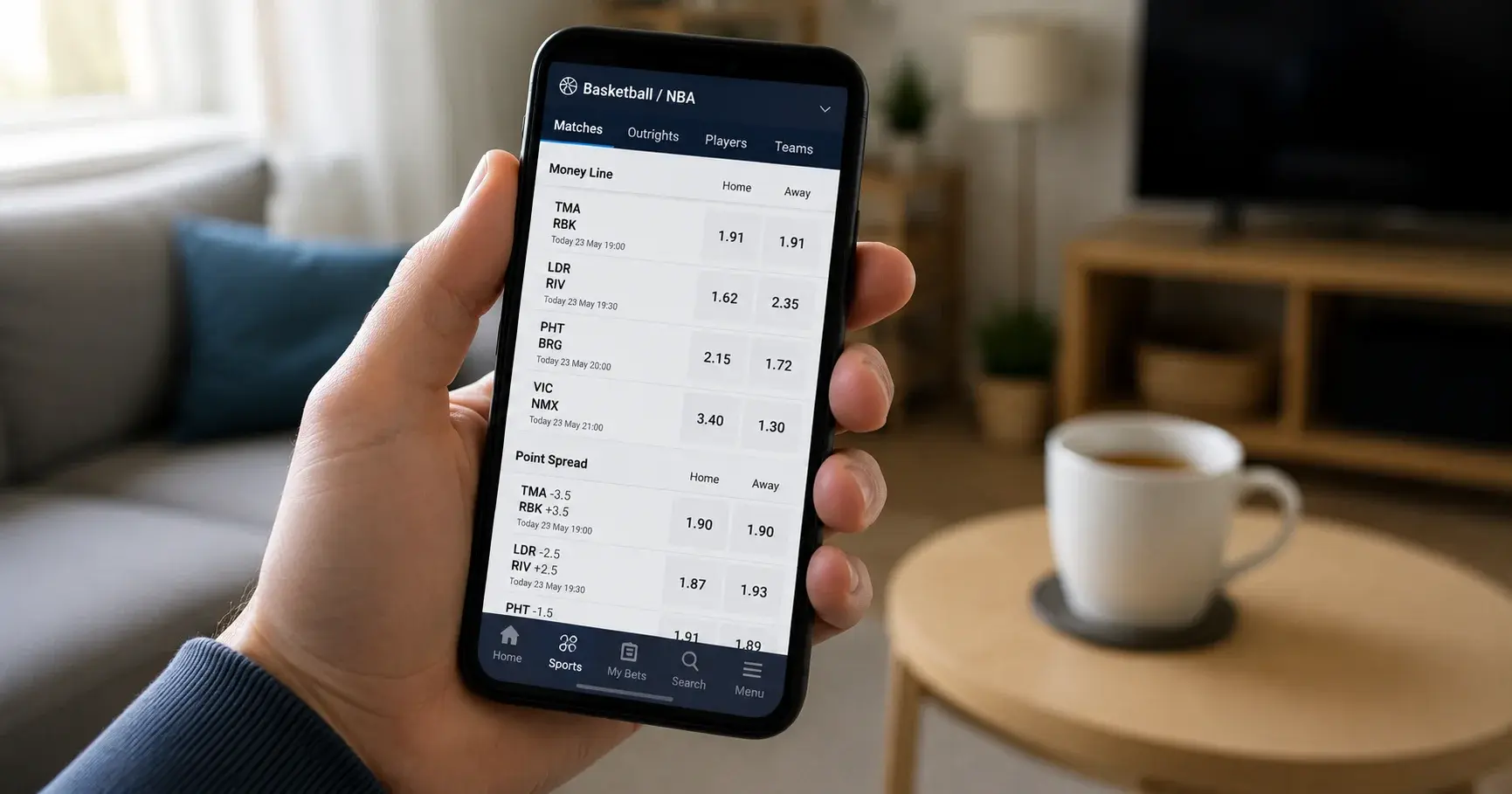Smartphone displaying NBA decimal odds on a UK bookmaker app with a cup of tea in the background